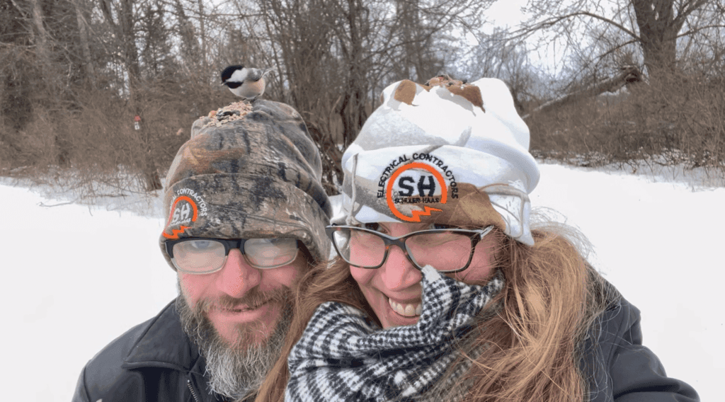 Black capped chickadee feeding off hat of Jacob and Francesca Gonzalez