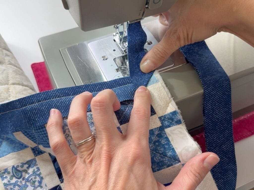 Sewing binding to a quilted table runner edge.