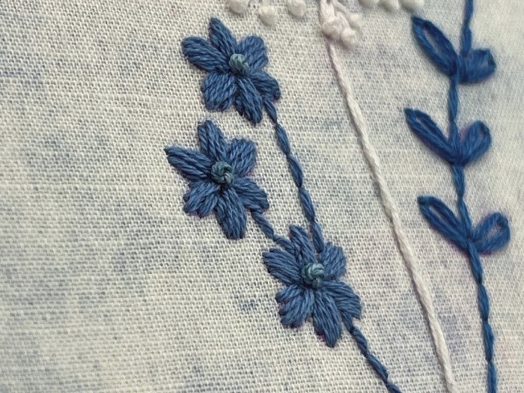 Close up of satin stitch flowers in blue/