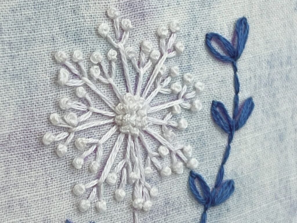 Close up of white flower done in fly stitch and french knots.